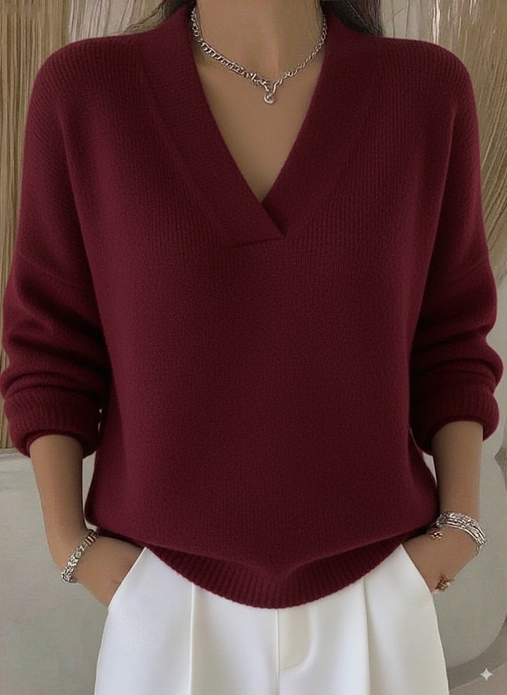 Burgundy relaxed V-neck knit sweater worn by a model with white trousers, front view