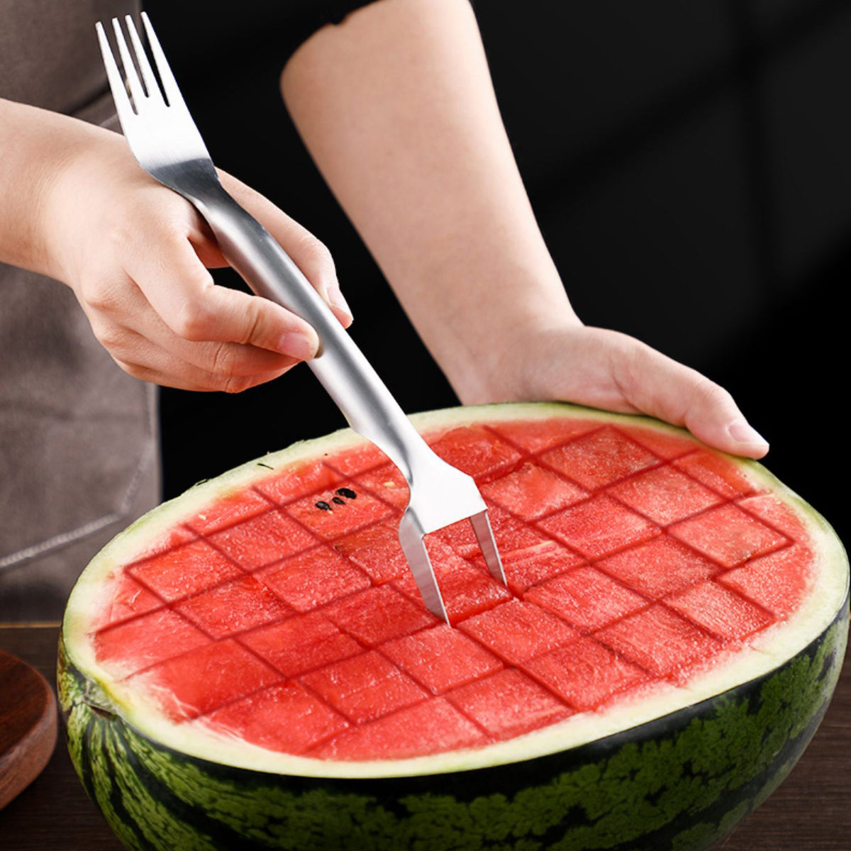 2-in-1 stainless steel watermelon fork and cutter, silver, being used to cut watermelon into cubes, close-up view