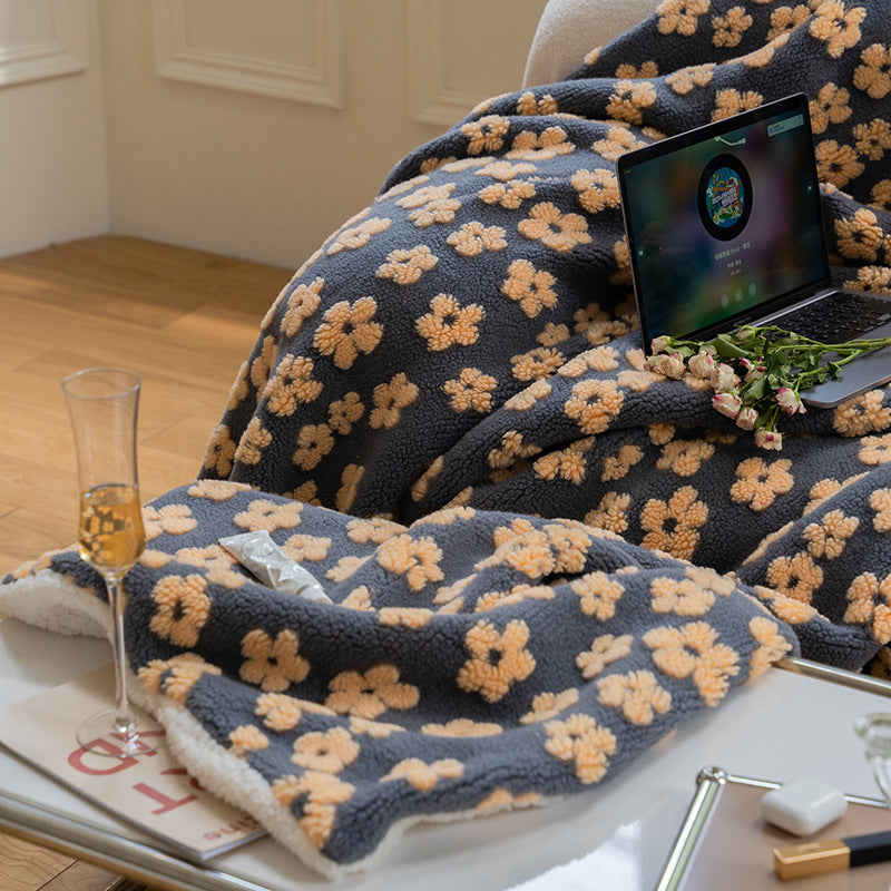 Floral jacquard sherpa-back throw blanket in navy with beige flowers, draped over a lap, shown in use with a laptop and