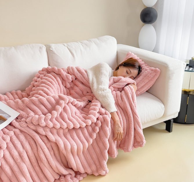 Pink ribbed throw covering a person on a white sofa