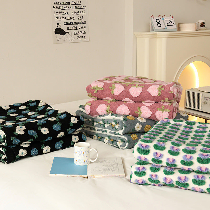 Double-Layer Tufted Flower Blanket in pink, green, blue and black floral patterns folded on a bed with a mug and notebook