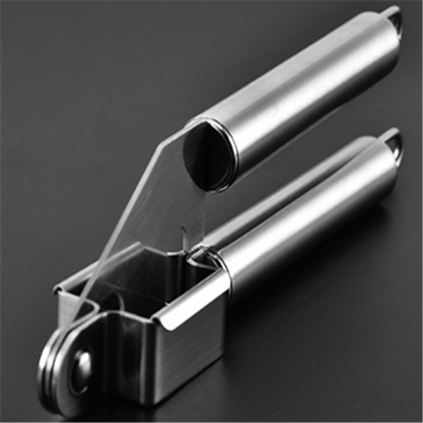 Side view of stainless steel garlic press with open chamber and handle alignment on dark surface