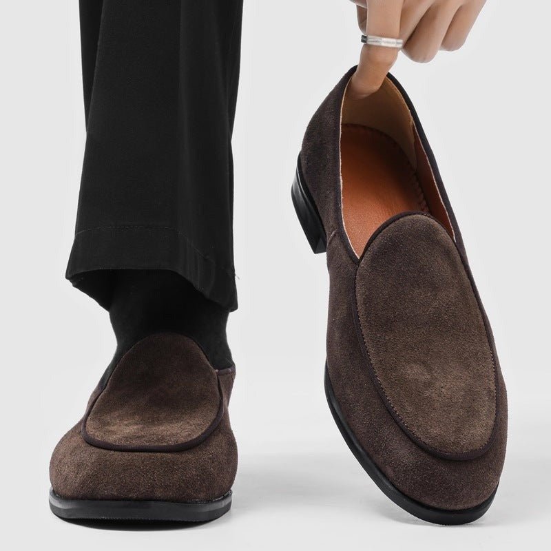 Brown suede-look men's slip-on loafer, worn on a foot with a black sock, second loafer held next to it