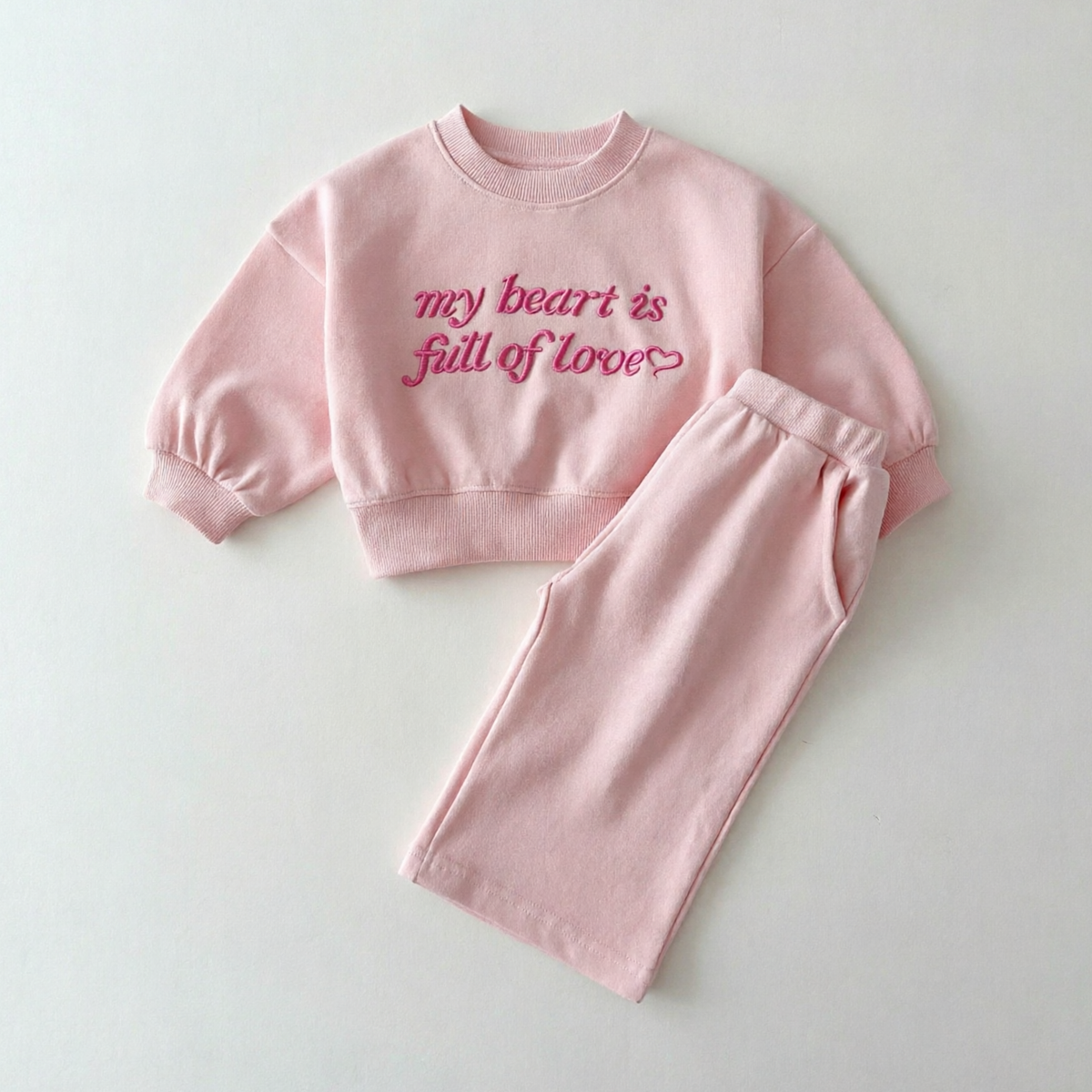 Roze sweater en broek met geborduurde tekst