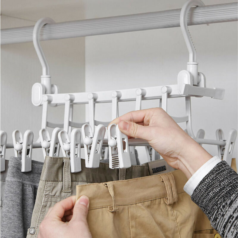 White 5-tier hanger with clips, hands adjusting clip on pants, close-up detail in use