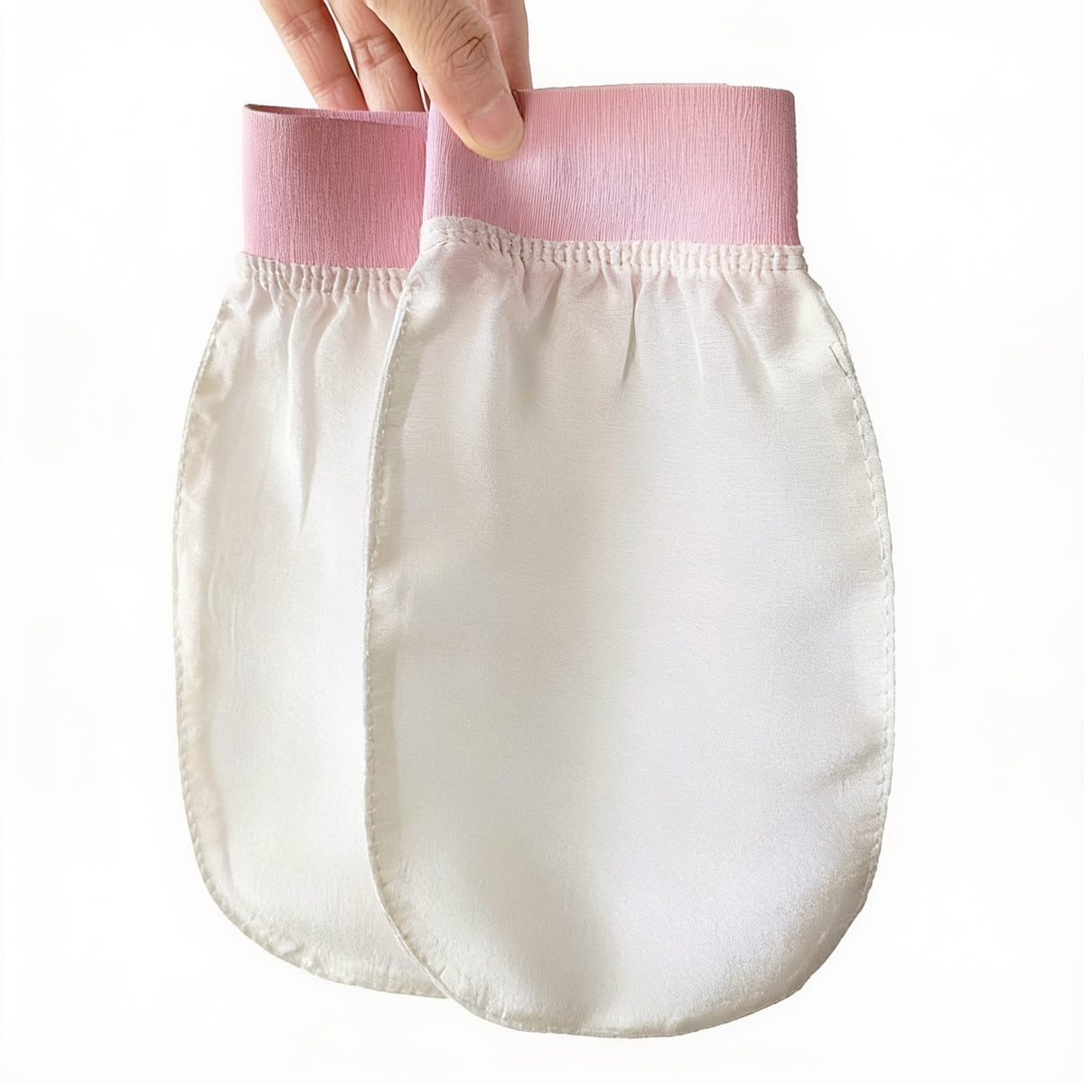 Hand die de roze boord vasthoudt van een gebroken witte viscose gezichtshandschoen naast een tweede identieke handschoen