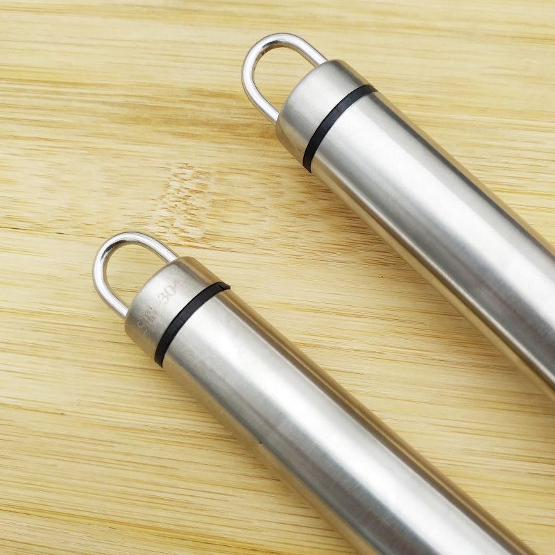 Detail view of stainless steel garlic press handles with hanging loops on wooden surface