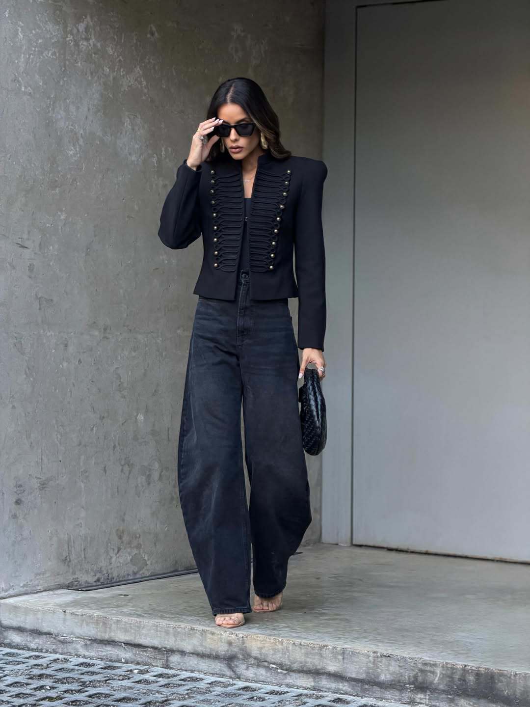 Full-length view of black cropped studded blazer worn with wide-leg black jeans