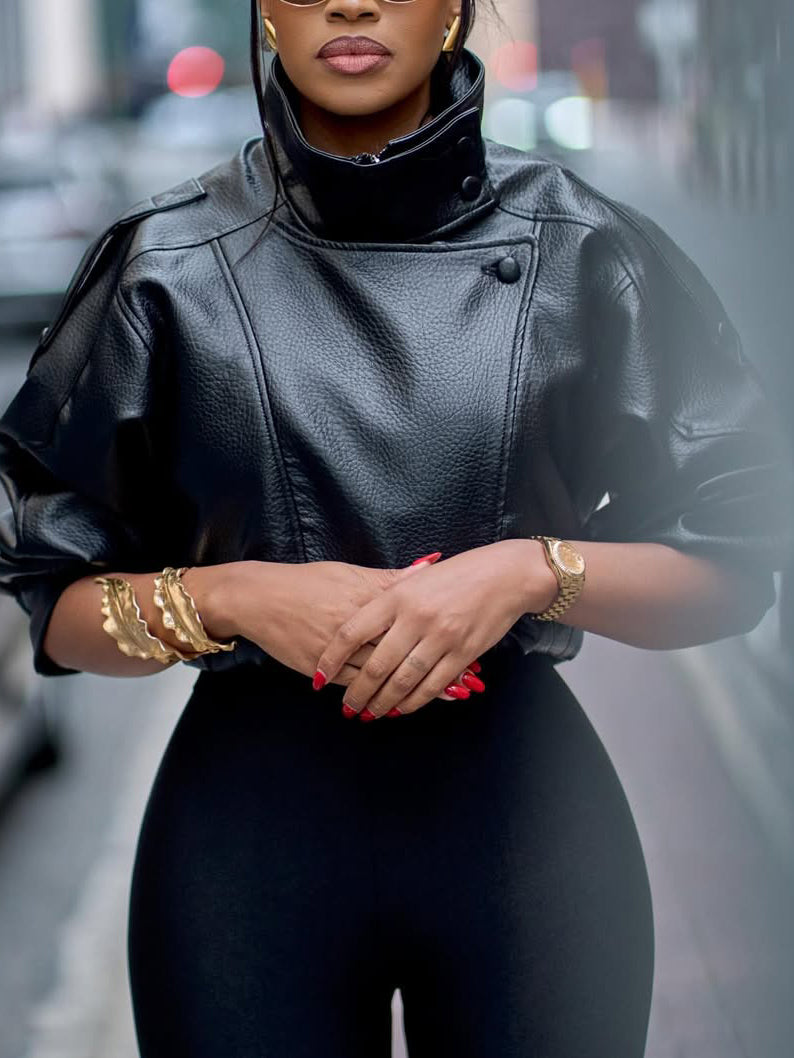 Black faux-leather cropped jacket with puff sleeves, stand collar, worn by model on city street, front view