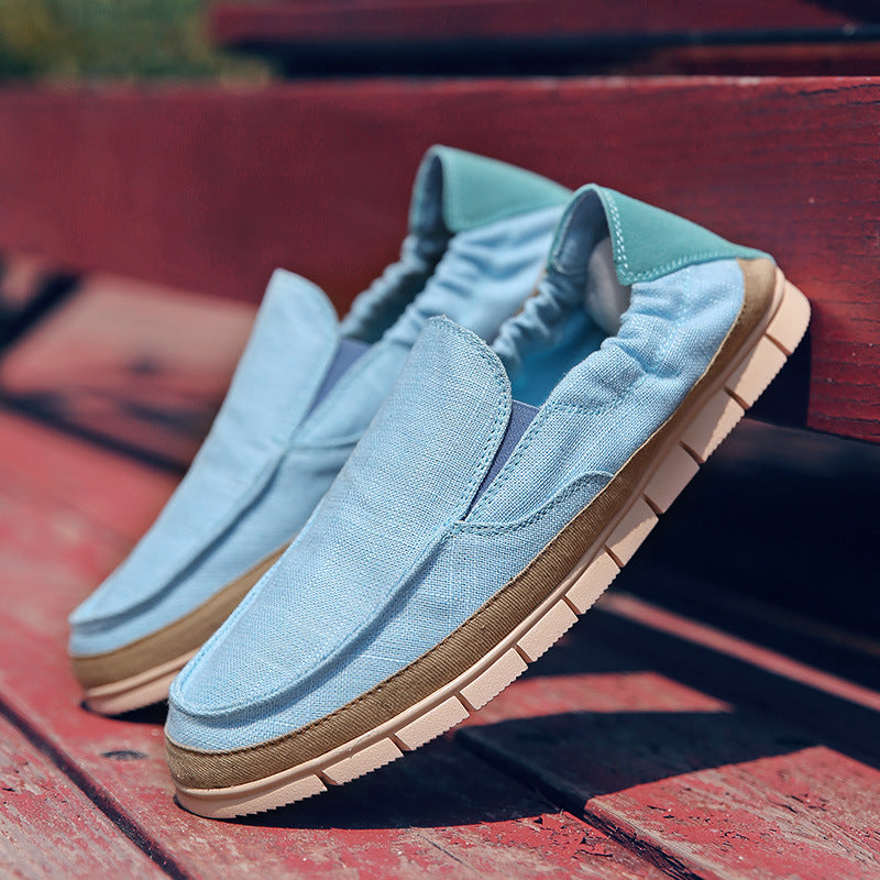 Linen-canvas slip-on loafer in sky blue, flat lay on red wooden bench, side view