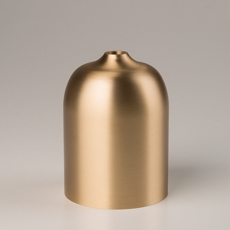 Brushed gold-tone metal bell-shaped vase on a neutral background