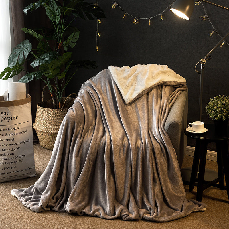 Reversible flannel throw in grey with cream sherpa lining, draped over armchair in living room setting