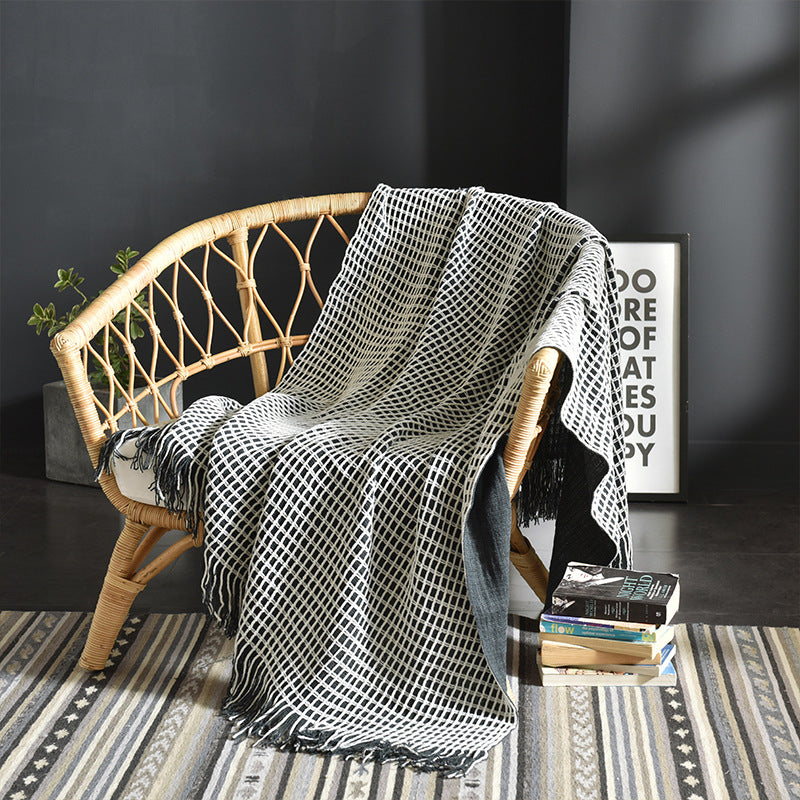 Waffle-weave throw blanket with black and off-white lattice pattern draped over a rattan chair