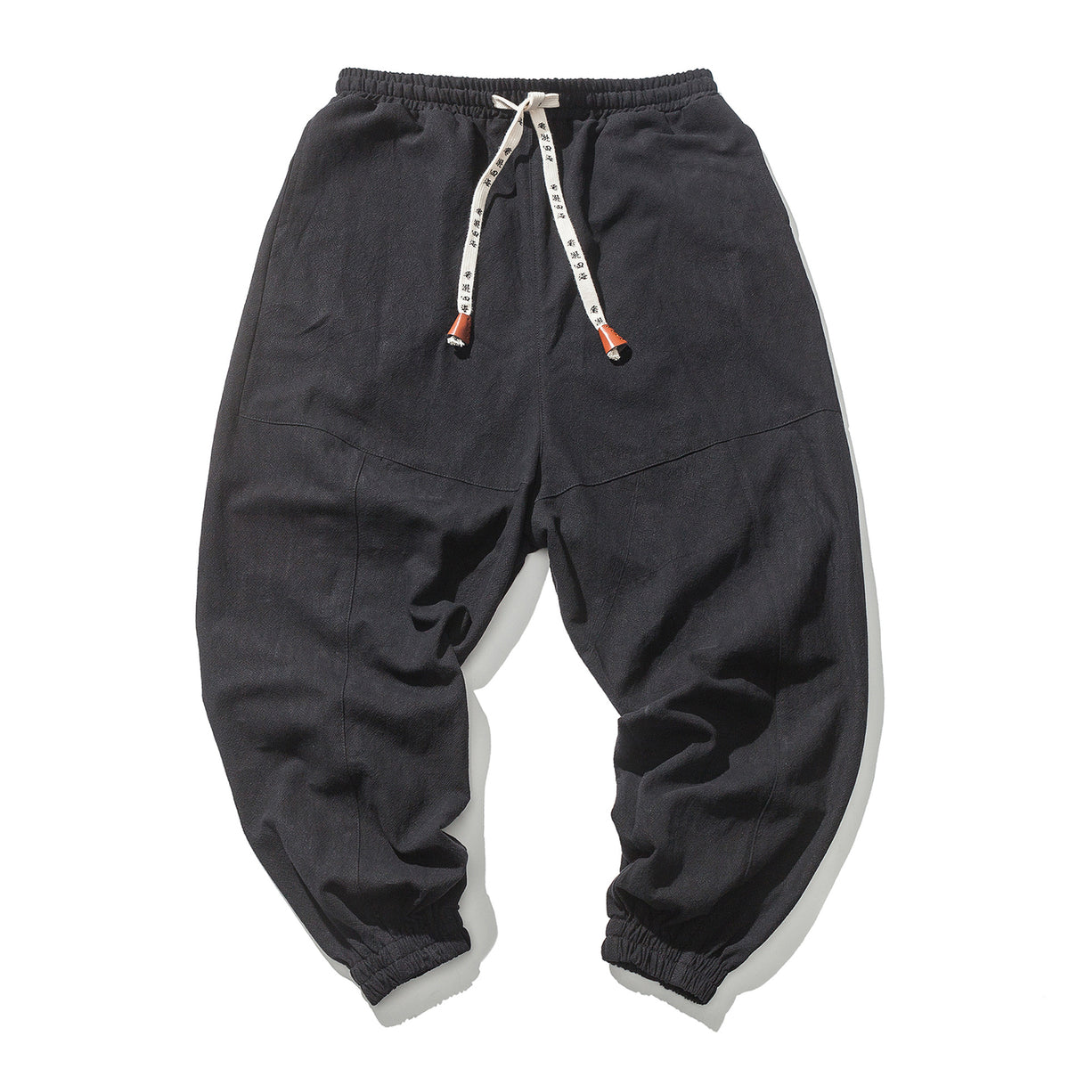 Black relaxed drop-crotch joggers, flat lay, front view, showing drawstring and ribbed cuffs