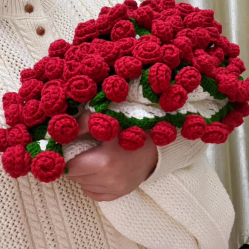 Crochet flower bouquet blanket in red roses, folded into a bouquet shape, held by a person wearing a white knitted sweater