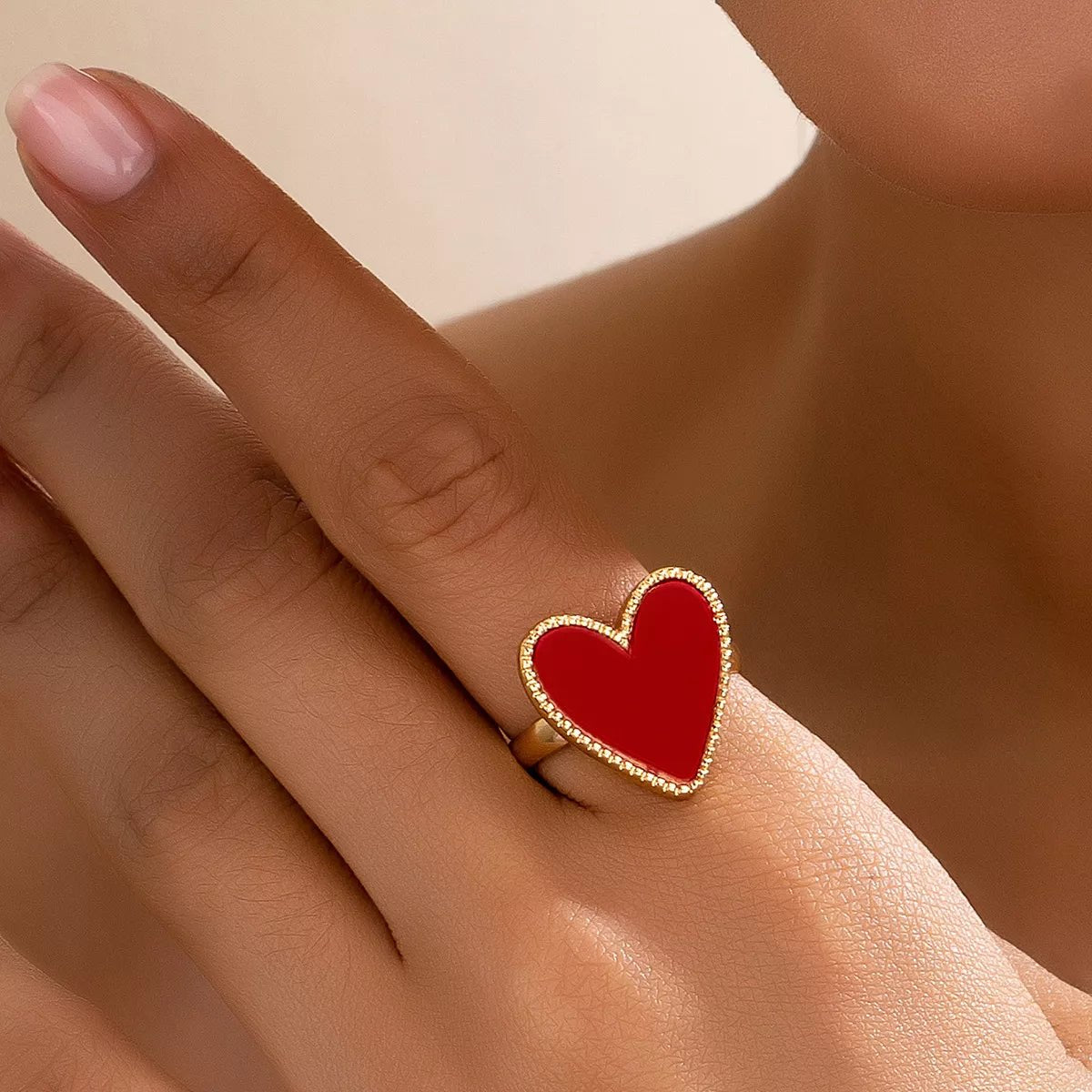 Gold-plated heart-shaped ring on model finger, elegant jewelry accessory