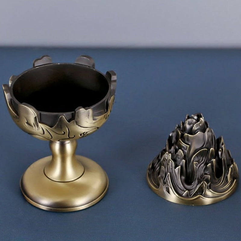 Incense burner with lid removed, showing bowl and mountain-shaped top, antique bronze-tone, on blue surface
