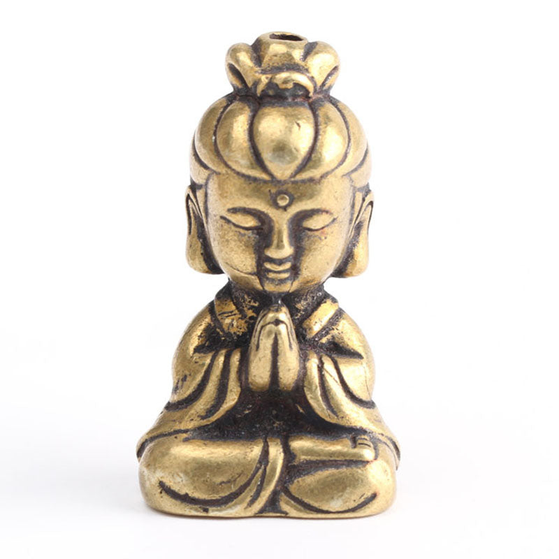 Small brass-look meditating figure ornament, front view, seated with praying hands and topknot, on white background