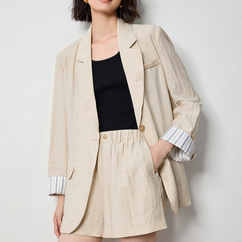 Loose-fit linen-look blazer in beige, single-breasted with gold-tone buttons, worn over black top and matching shorts on