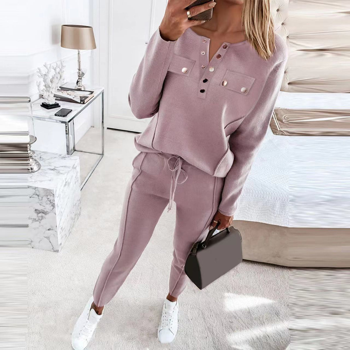 Model wearing dusty pink button-placket sweatshirt and drawstring trousers with white sneakers