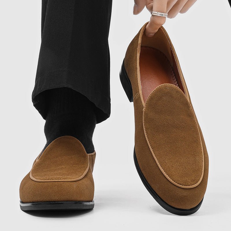 Tan suede-look men's slip-on loafer, worn on a foot with a black sock, second loafer held next to it