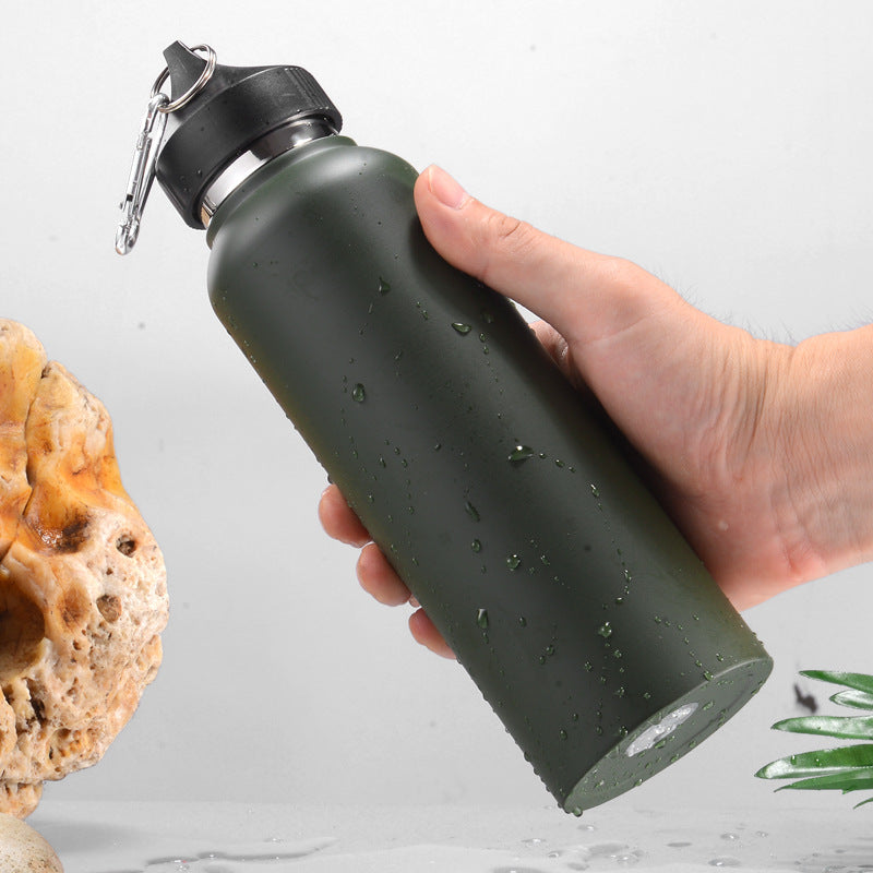 Hand holding olive green stainless steel vacuum bottle with carabiner lid, showing grip and water droplets on surface