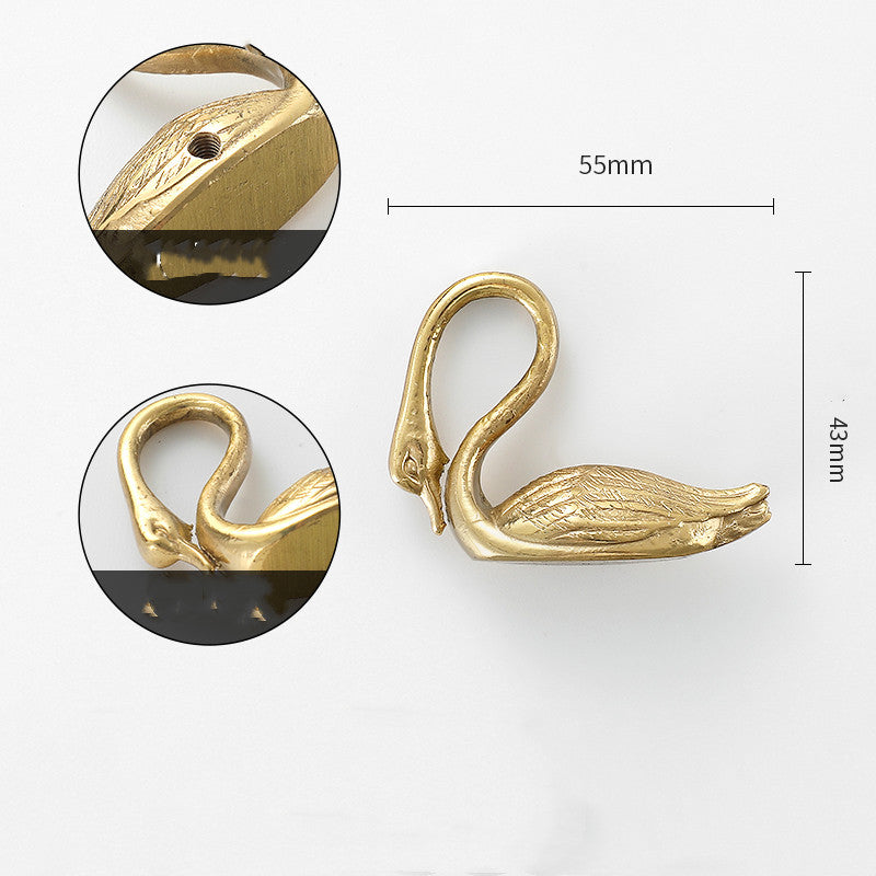 Gold-tone swan-shaped cabinet knob, side view with detail of neck and screw hole, flat lay on white background