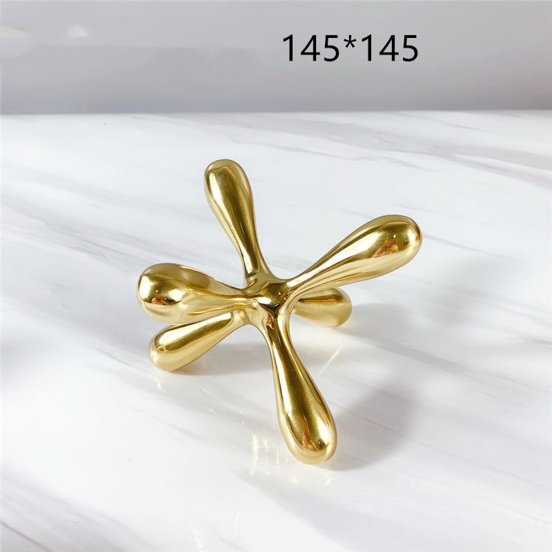 Gold-tone metal jacks sculpture, 145x145 mm, front view, on marble surface