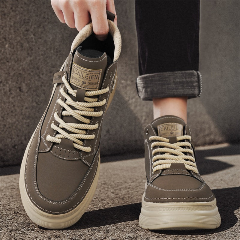 Men's high-top lace-up sneaker boots in grey, worn on feet, one shoe lifted, outdoor setting