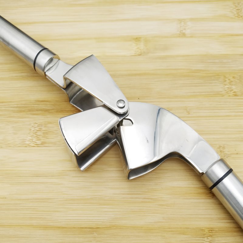 Close-up of stainless steel garlic press hinge and pressing mechanism on wooden surface