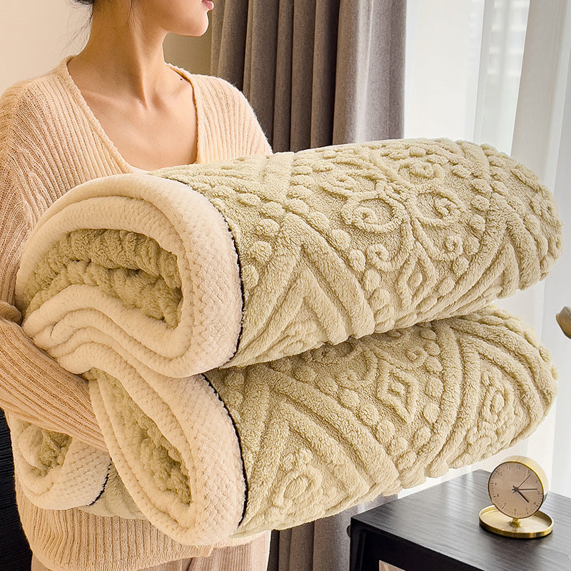 Embossed diamond-pattern velvet-look blanket in beige, rolled and held by a person, showing texture and thickness