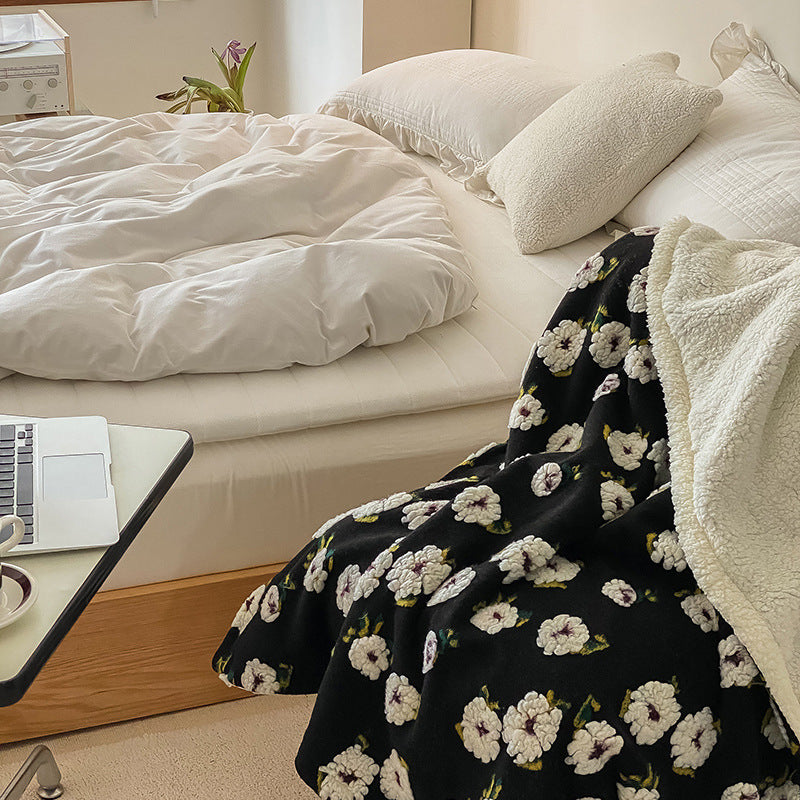 Double-Layer Tufted Flower Blanket with white flowers on black background draped over a bed beside a laptop and small table