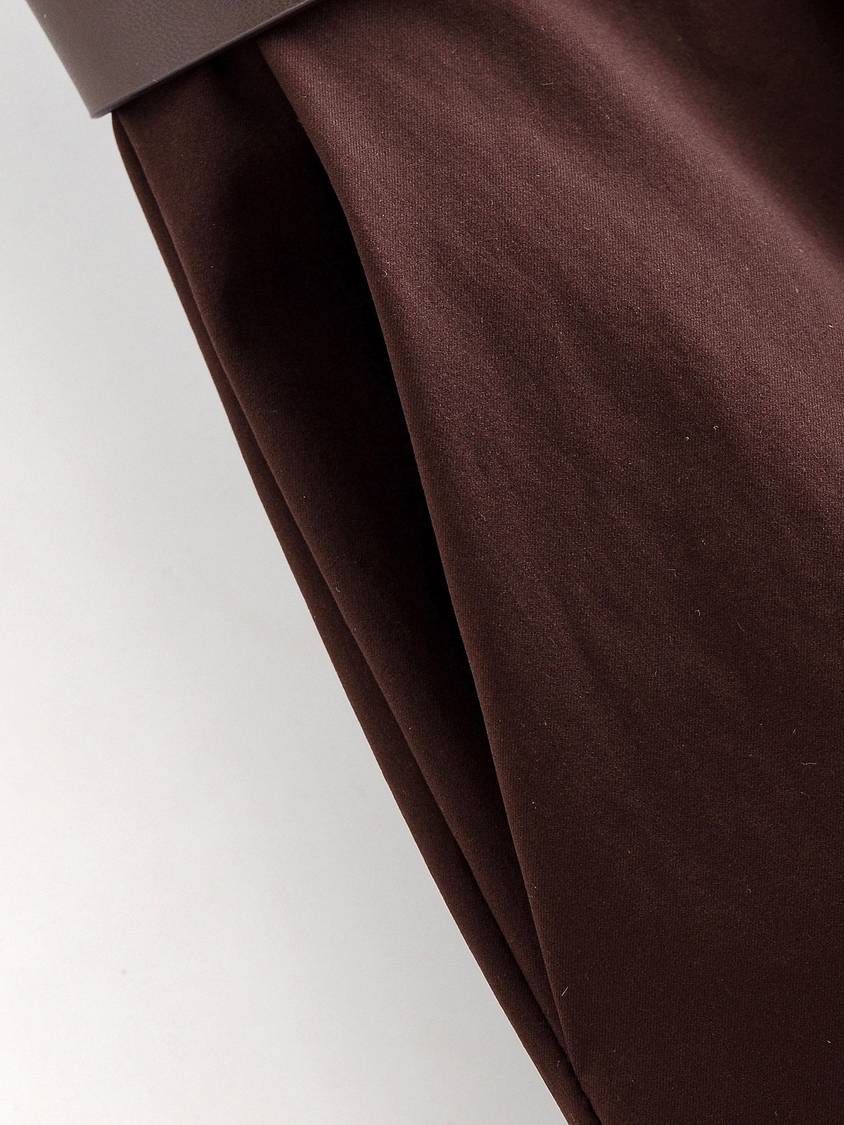 Close-up of the side pocket seam on chocolate brown wide-leg trousers