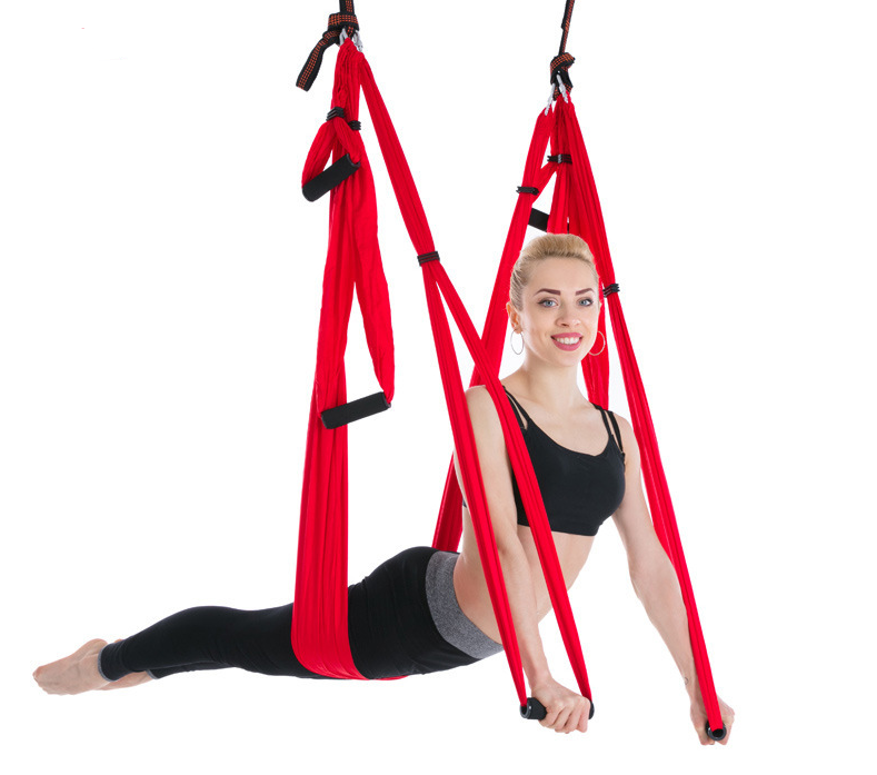 Red aerial yoga hammock with handles, model in a reclined pose holding the handle straps