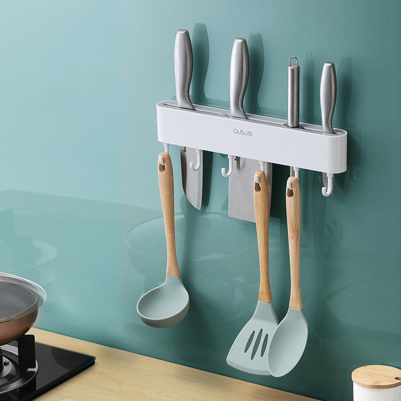 Wall-mounted magnetic knife bar with hooks, white, holding knives and hanging utensils, side view in kitchen setting