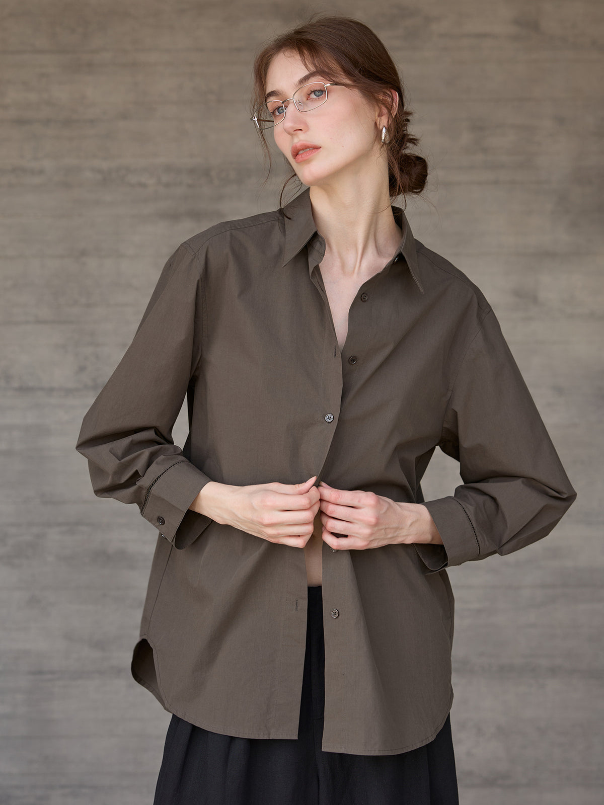 Relaxed long-sleeve shirt with dropped shoulder in dark brown, worn by a model, front view, hands buttoning the shirt