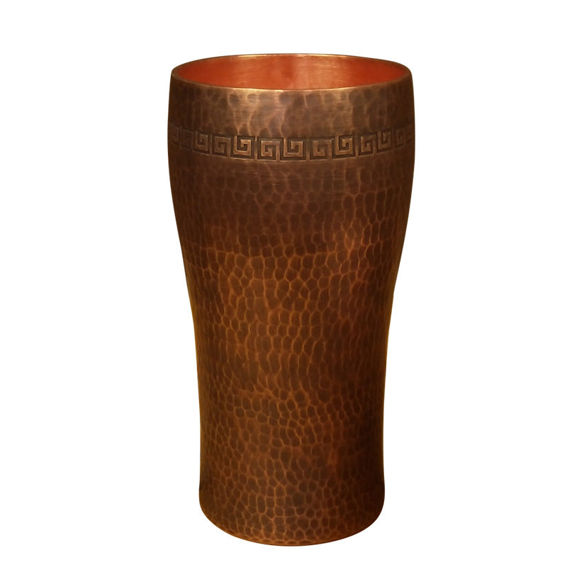 Curved hammered copper beer tumbler with Greek-key border, white background