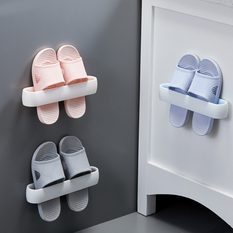 Two wall-mount slipper racks in white and grey, holding pink and blue slippers, mounted on grey wall and white door, in use