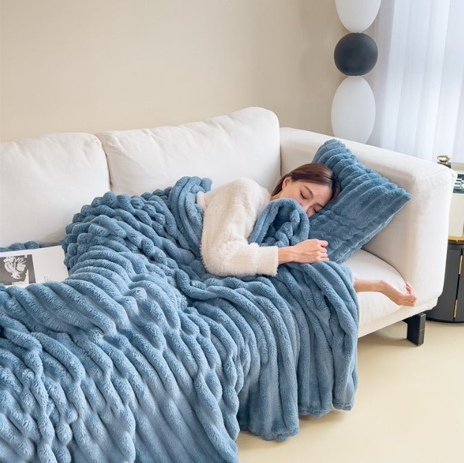Blue ribbed throw covering a person on a white sofa