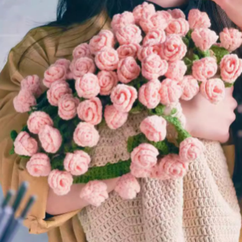 Crochet flower bouquet blanket in pink roses, folded into a bouquet shape, held by a person wearing a yellow top, indoors