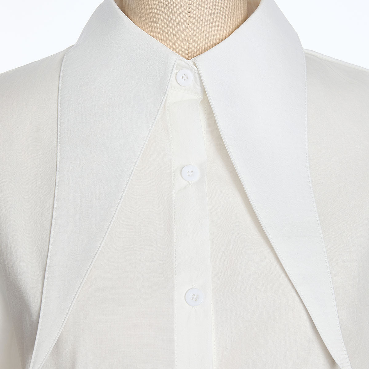 Close-up of the white shirt collar and button placket, showing the wide pointed collar and small white buttons