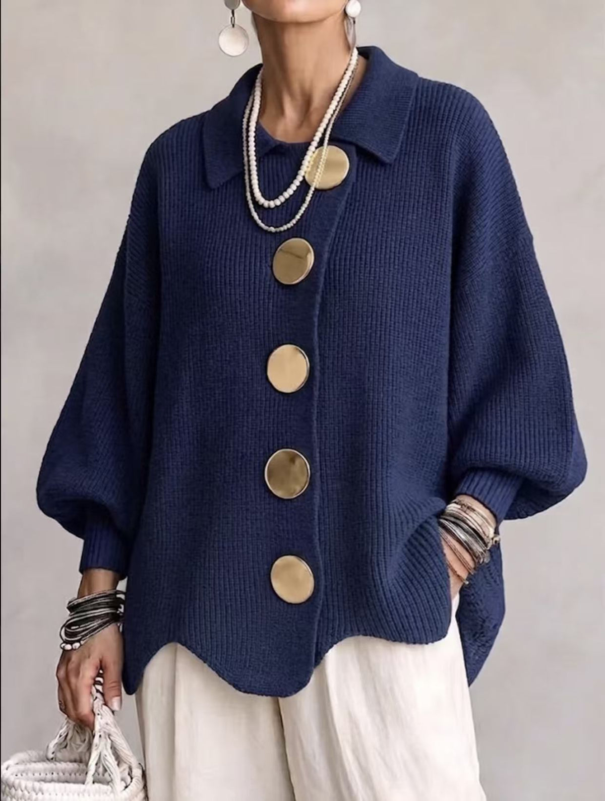 Collared knit cardigan in navy blue with large gold buttons, worn on a model, front view, wavy hem, dropped shoulders