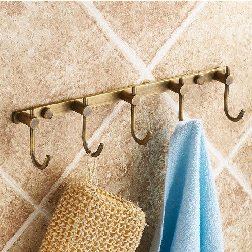 5-hook wall rail in antique brass-tone finish on a tiled wall, with a towel and a bath sponge