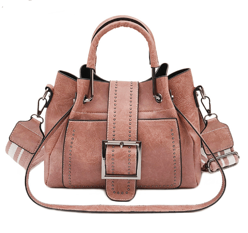 Pink structured bucket-style handbag in dusty rose, front view with buckle flap, stud trim and shoulder strap