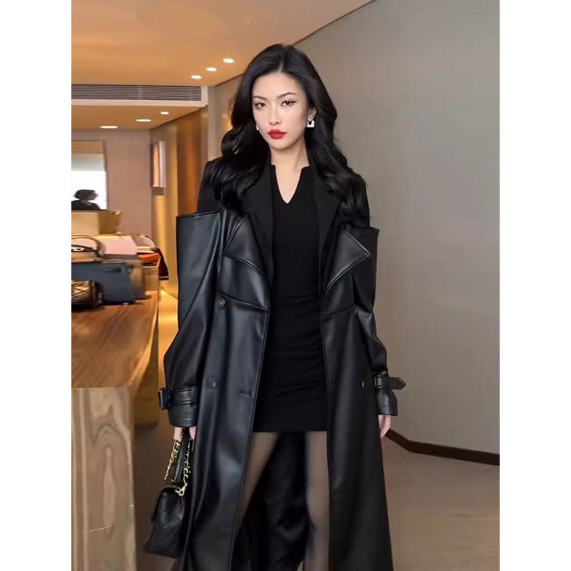 Front view of long black trench coat with contrast shoulders, double-breasted, worn by a model in an indoor setting