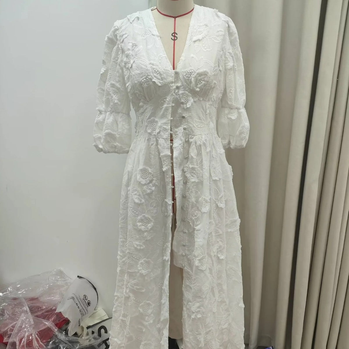 Front view of white embroidered puff-sleeve dress with button front displayed on a mannequin in a studio setting