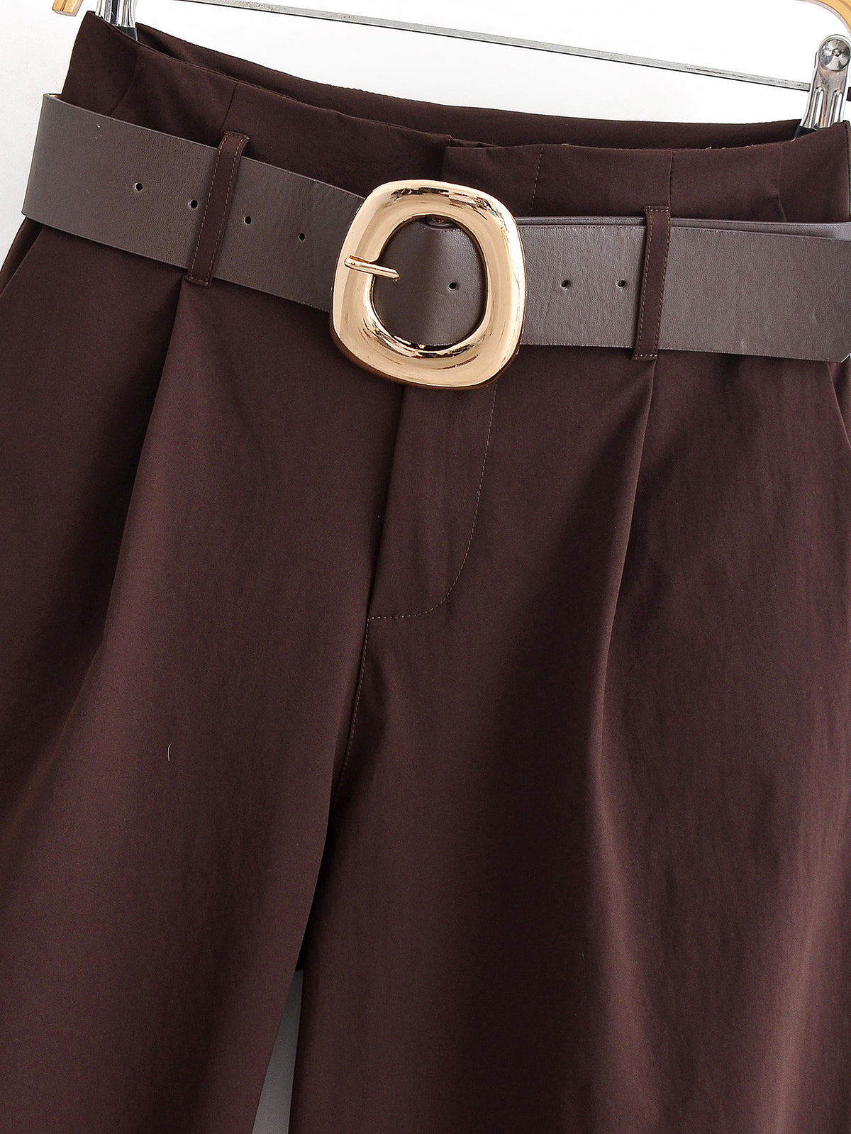 Close-up front view of the waist of chocolate brown trousers with pleats and a wide brown belt