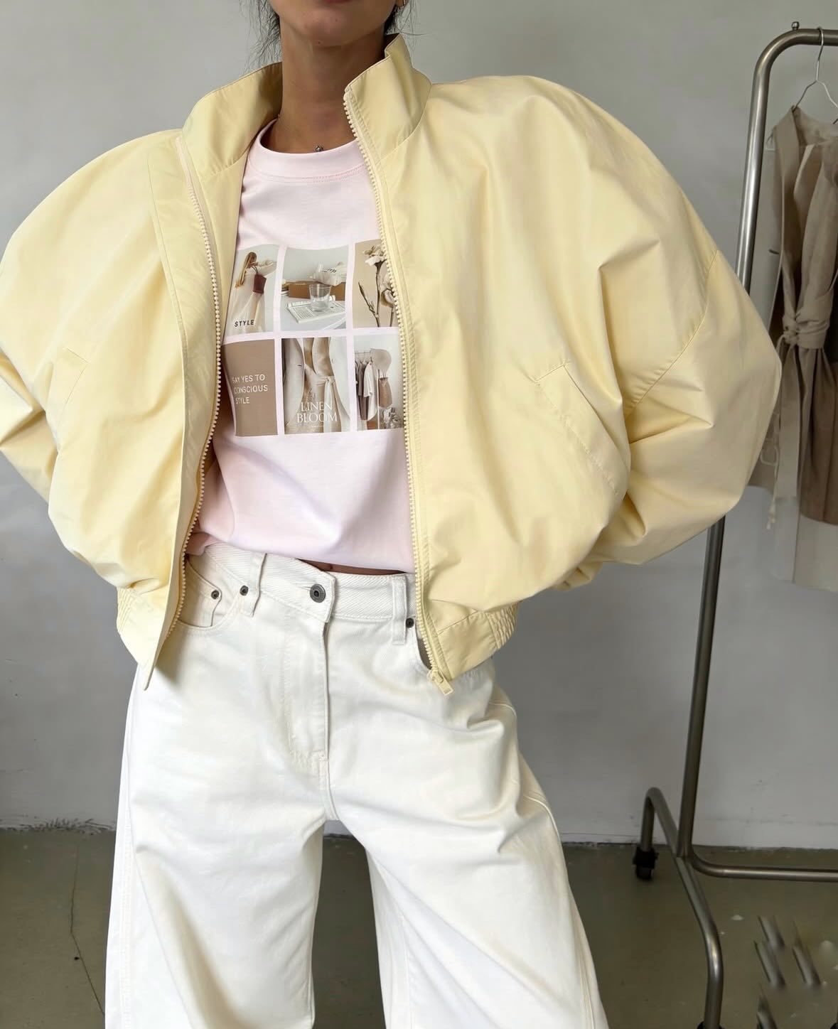 Pale yellow cropped bomber jacket, front view on model, full zip closed, loose fit, stand collar