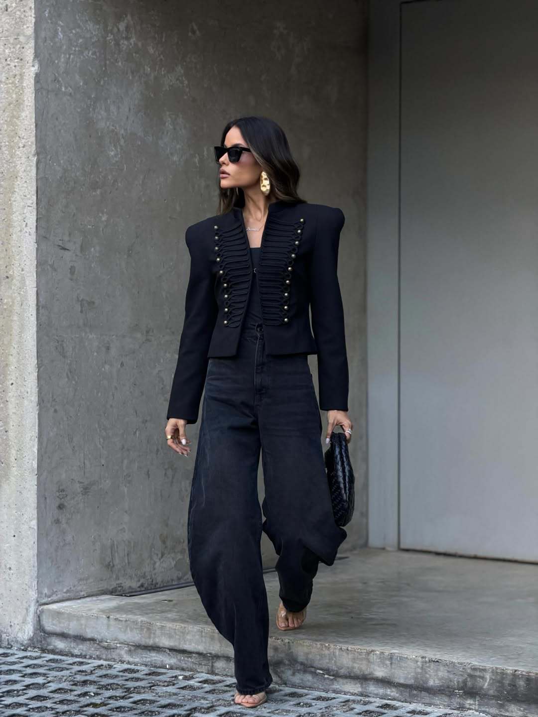 Black cropped blazer with stud detail, side view on a model walking