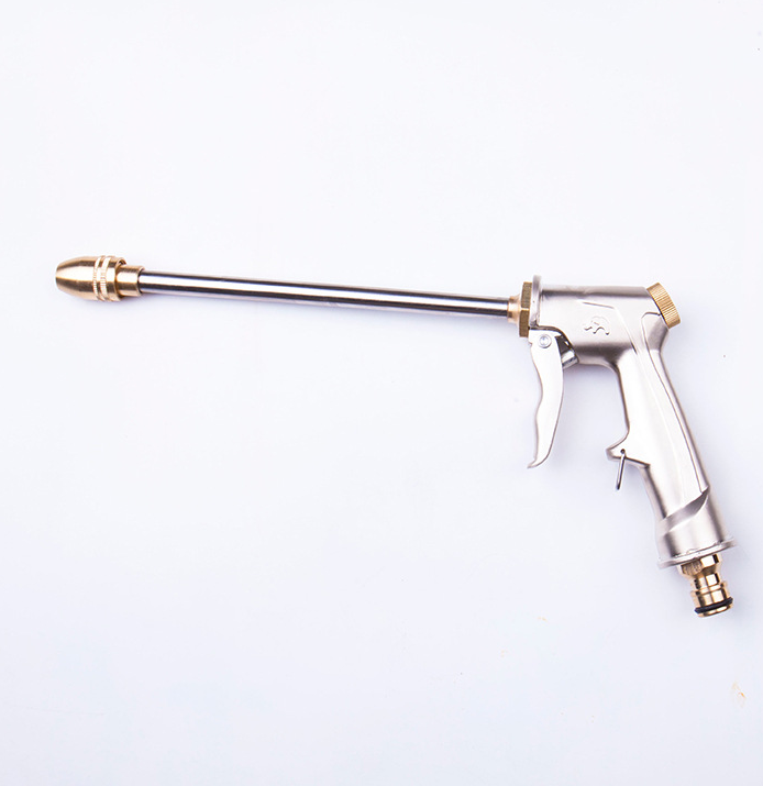 Flat lay of garden hose spray gun, full view, silver and brass-tone, lying on white surface